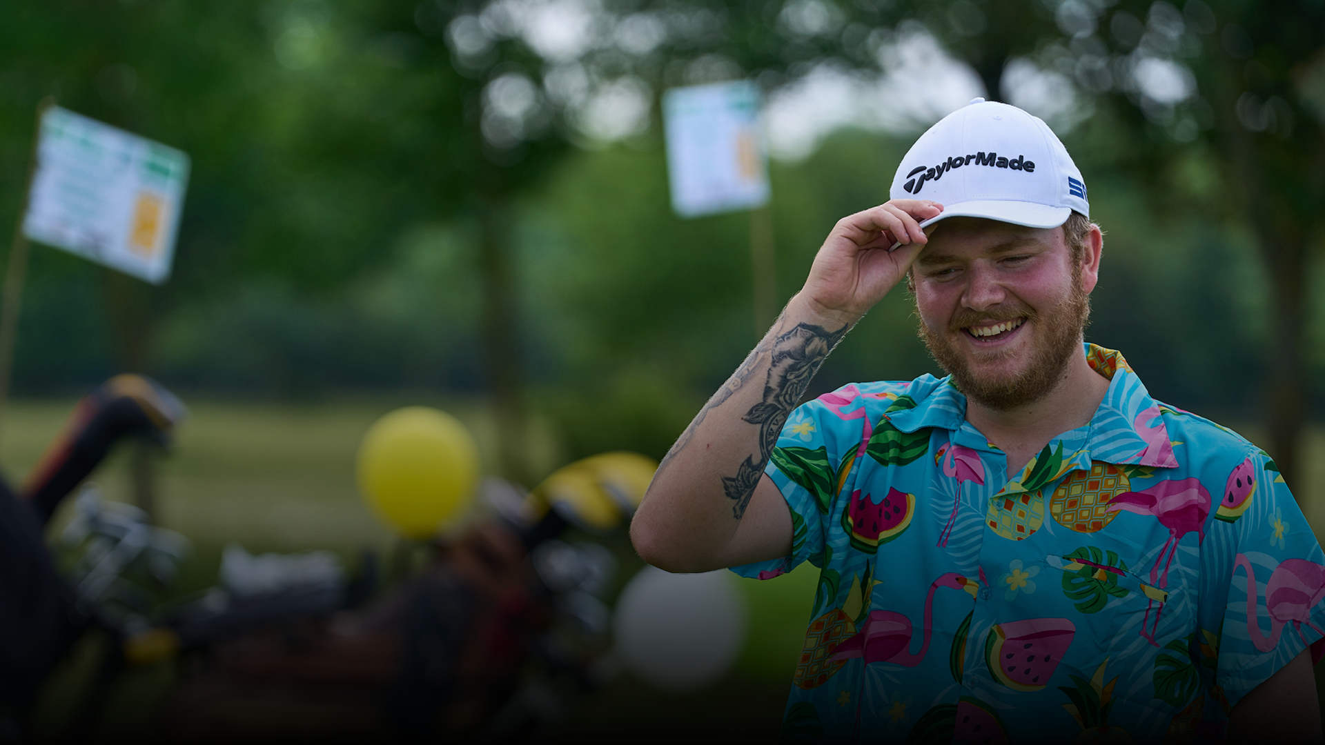 A golfer wearing a hat with a cheerful expression, displaying a warm smile.