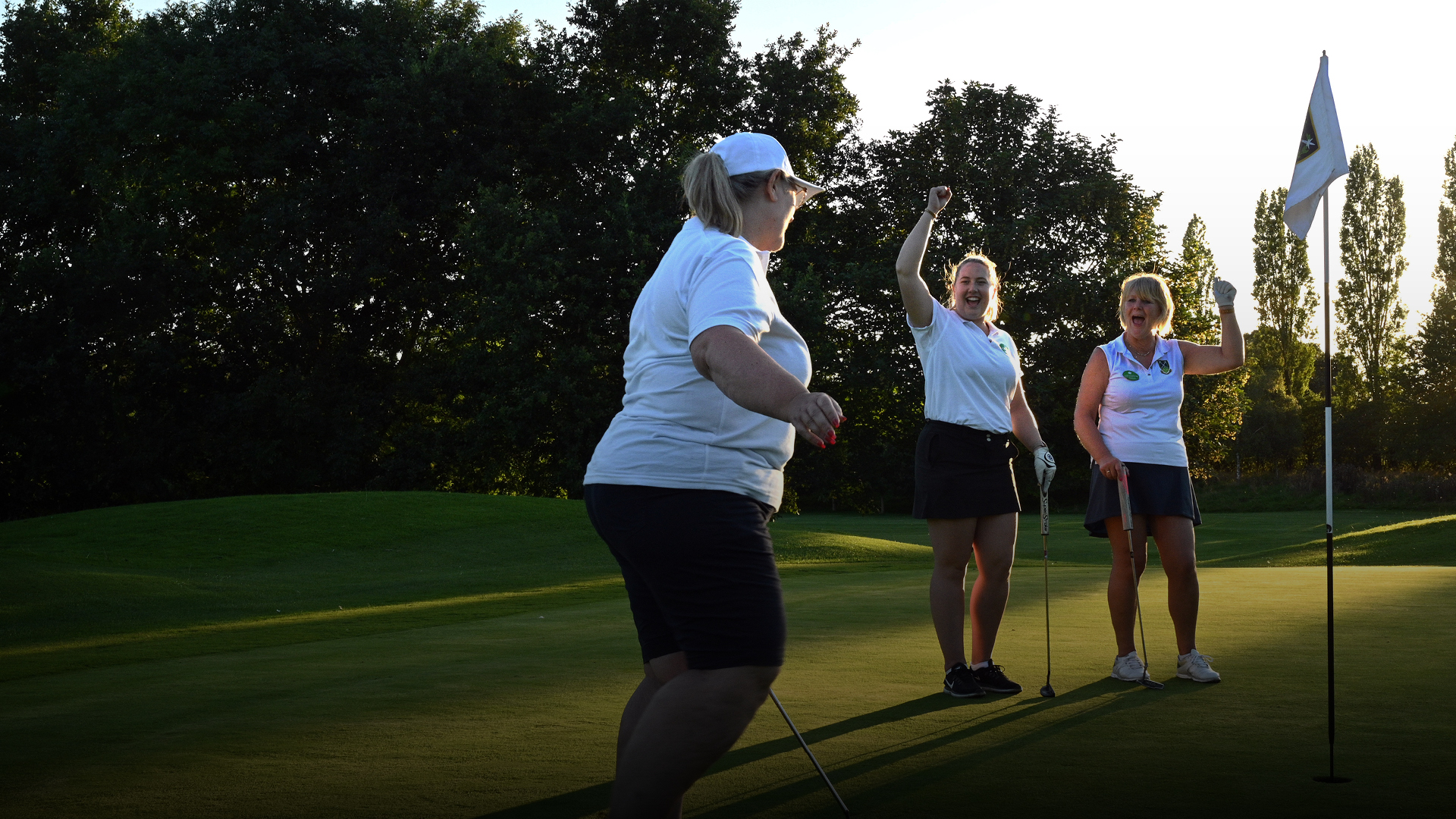 Three golfers on a golf course with their golf equipment