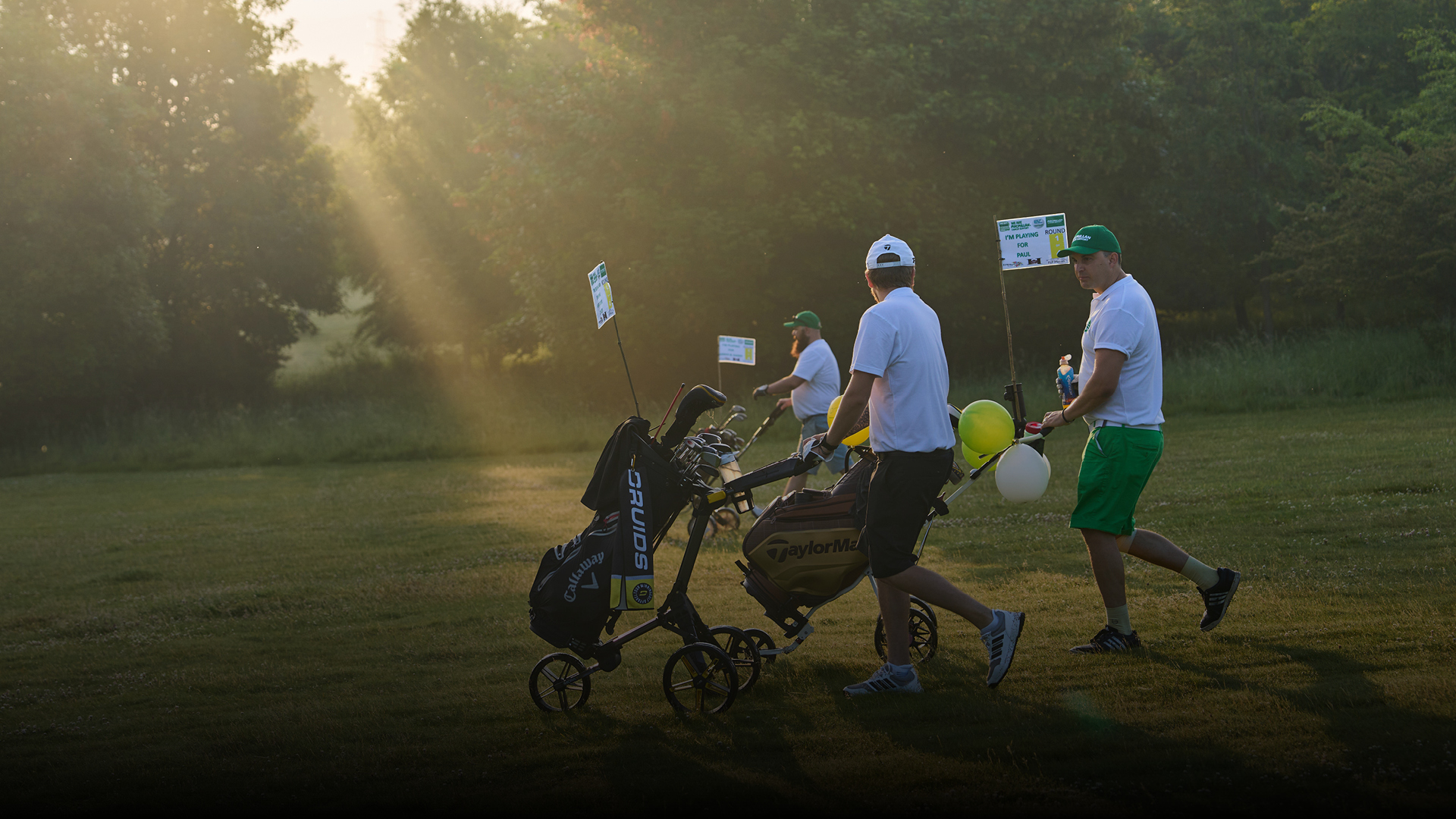 A group of people pushing a caddie on a golf course